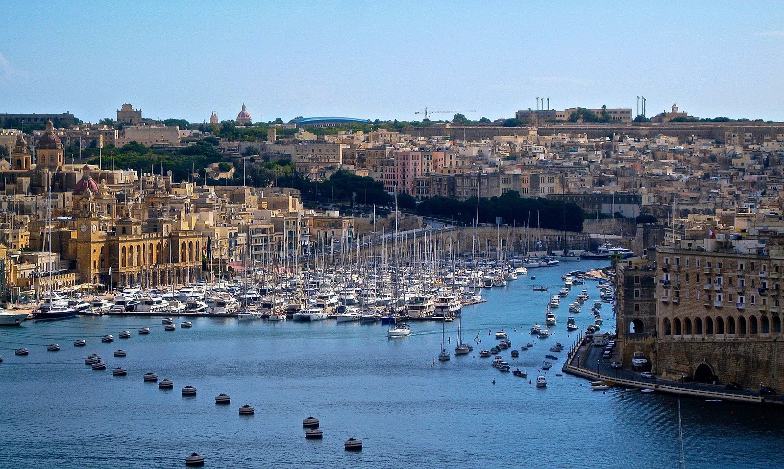 Vue sur un port pittoresque à Malte, avec des bateaux amarrés et des bâtiments en arrière-plan