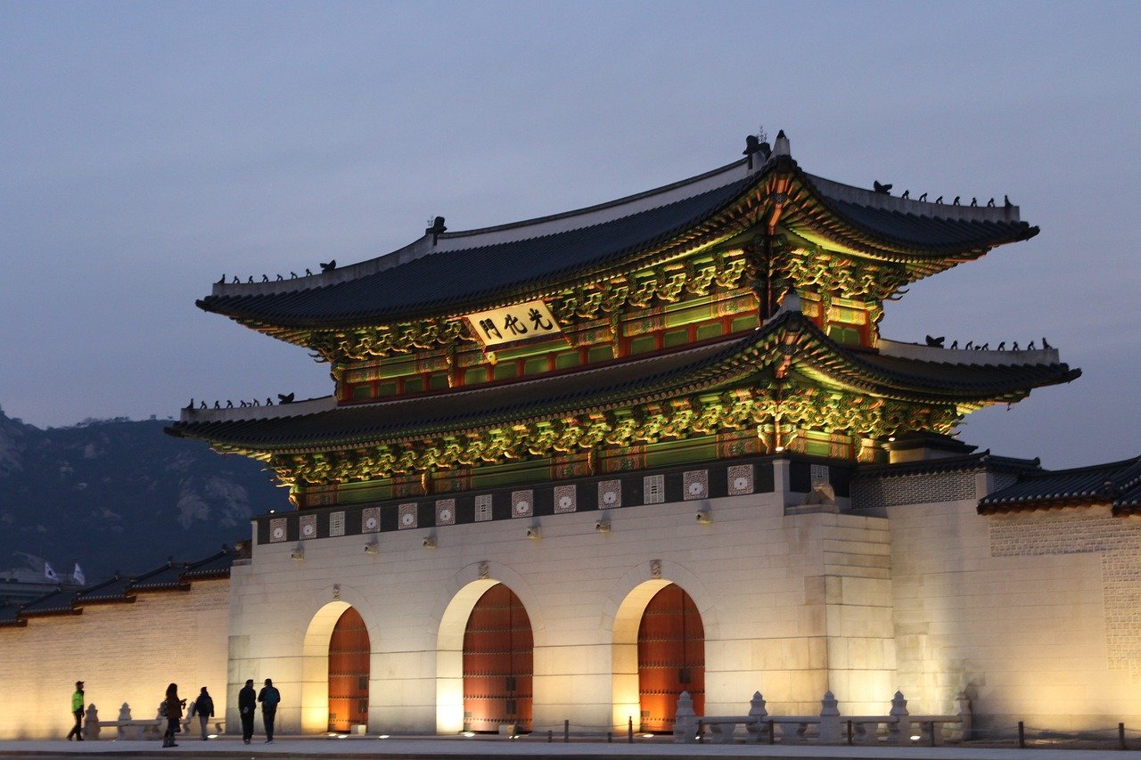 Vue de l'extérieur d'un palais à Séoul, avec son architecture traditionnelle coréenne, ses toits incurvés et ses éléments décoratifs complexes, offrant un aperçu de l'histoire et de la culture de la Corée du Sud