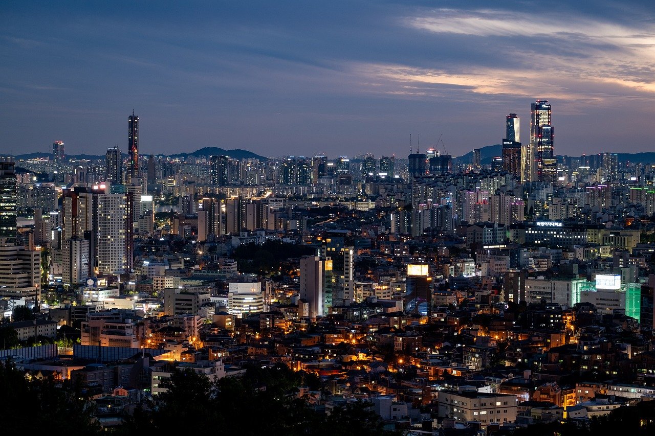 Vue sur les buildings de Séoul, de nuit, illuminés par des lumières vibrantes et modernes, créant une atmosphère dynamique dans la capitale sud-coréenne, où la skyline urbaine se reflète dans le ciel nocturne