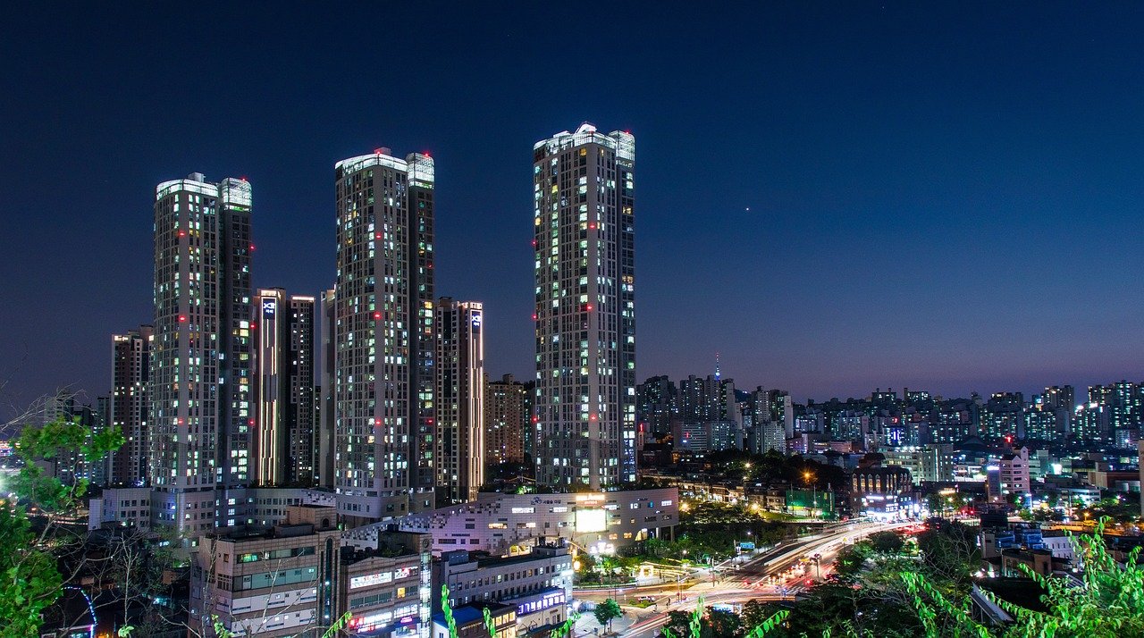 Vue sur les buildings de Séoul, de nuit, illuminés par des lumières vibrantes et modernes, créant une atmosphère dynamique dans la capitale sud-coréenne, où la skyline urbaine se reflète dans le ciel nocturne