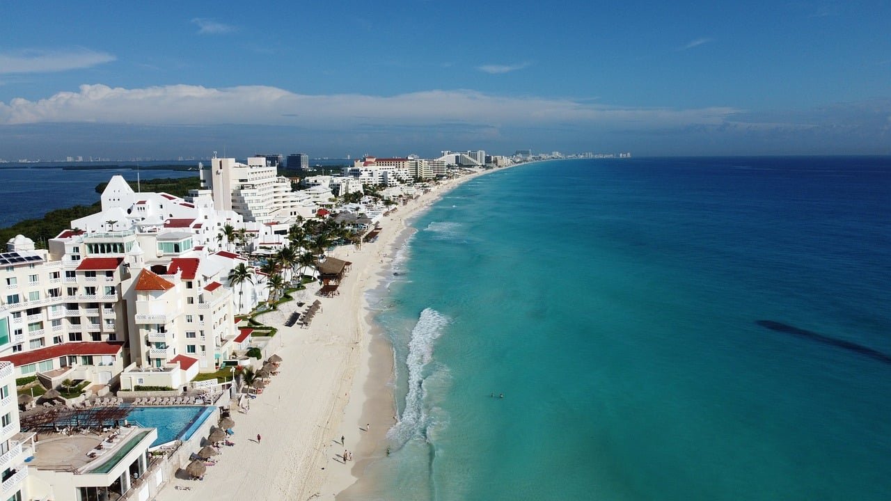 Vue aérienne sur la plage de Cancún, Mexique, mettant en évidence ses eaux turquoise et son sable blanc, bordée d'hôtels et de palmiers