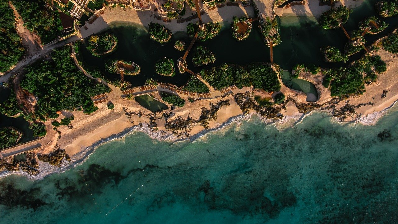 Vue aérienne sur la plage de Cancún, Mexique, mettant en évidence ses eaux turquoise et son sable blanc, bordée d'hôtels et de palmiers