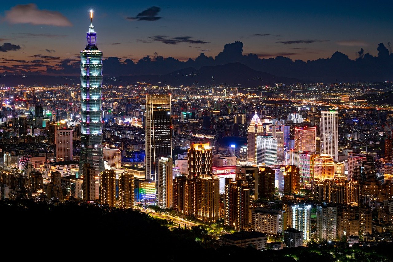 Vue panoramique sur Taipei la nuit, avec ses gratte-ciel illuminés, incluant le célèbre Taipei 101, et un ciel étoilé qui met en valeur la silhouette vibrante de la ville