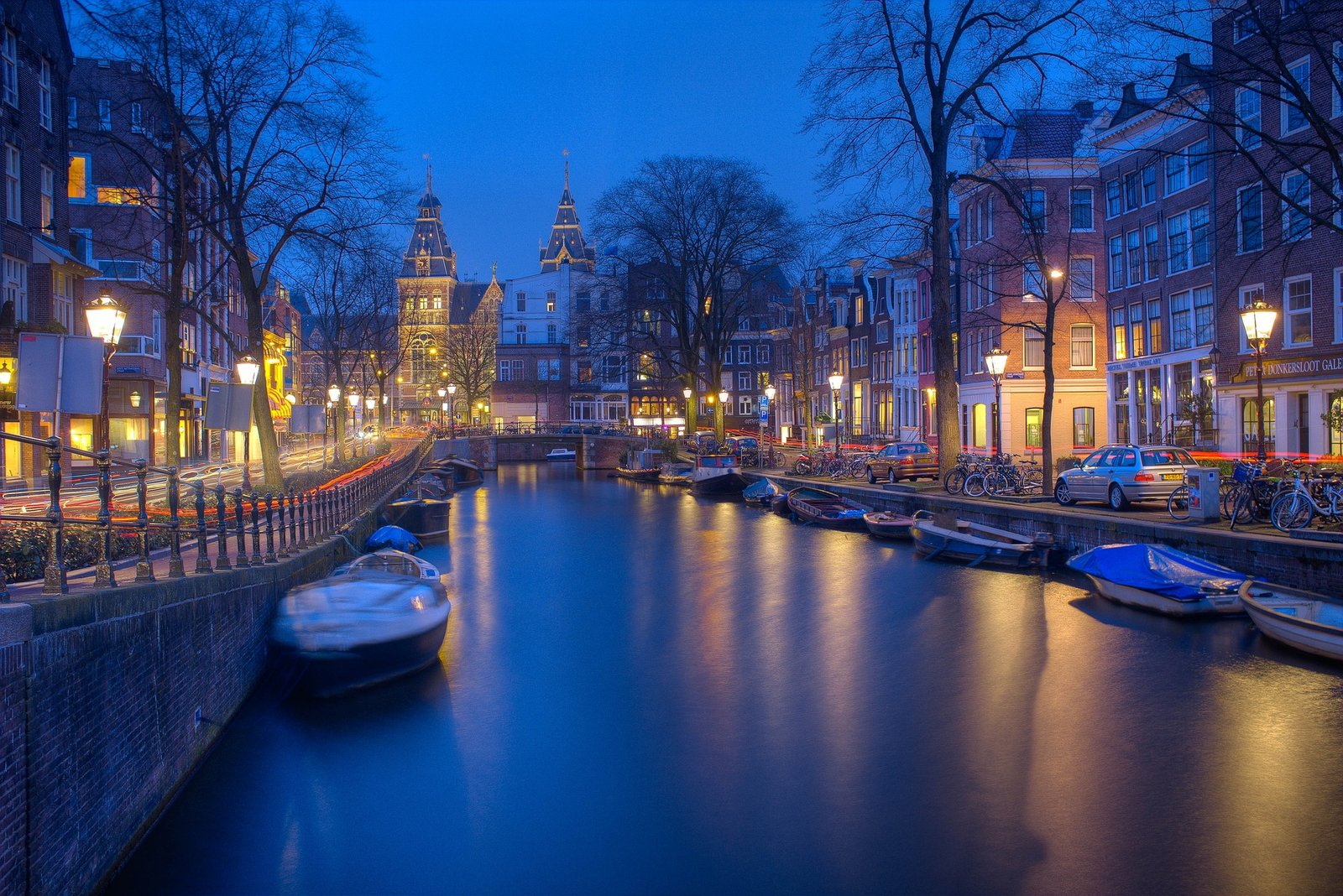 Vue sur l'Amstel en plein cœur d'Amsterdam au coucher du soleil, avec ses canaux scintillants, ses ponts emblématiques et ses maisons typiques à façades étroites