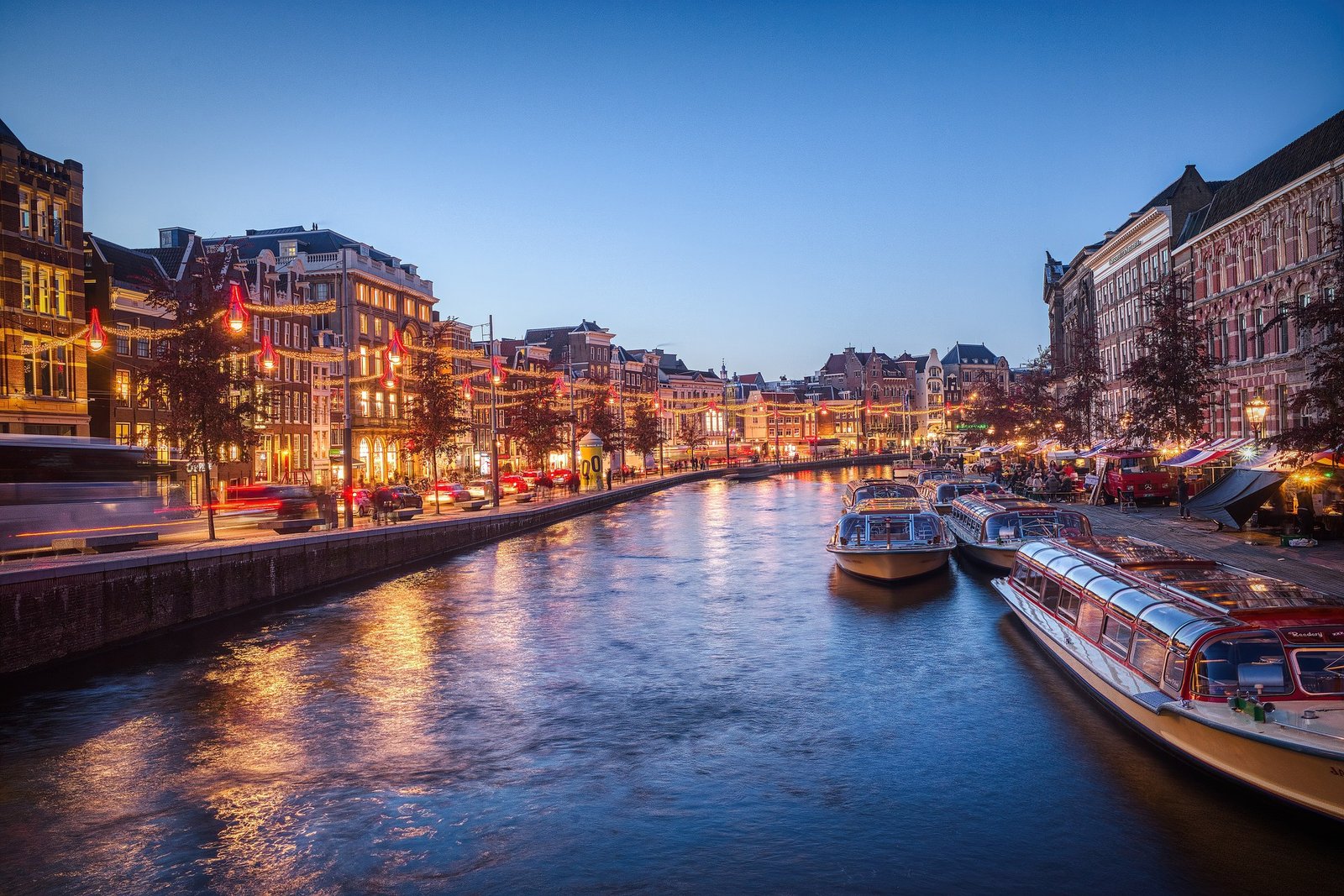 Vue sur l'Amstel en plein cœur d'Amsterdam au coucher du soleil, avec ses canaux scintillants, et ses maisons typiques à façades étroites