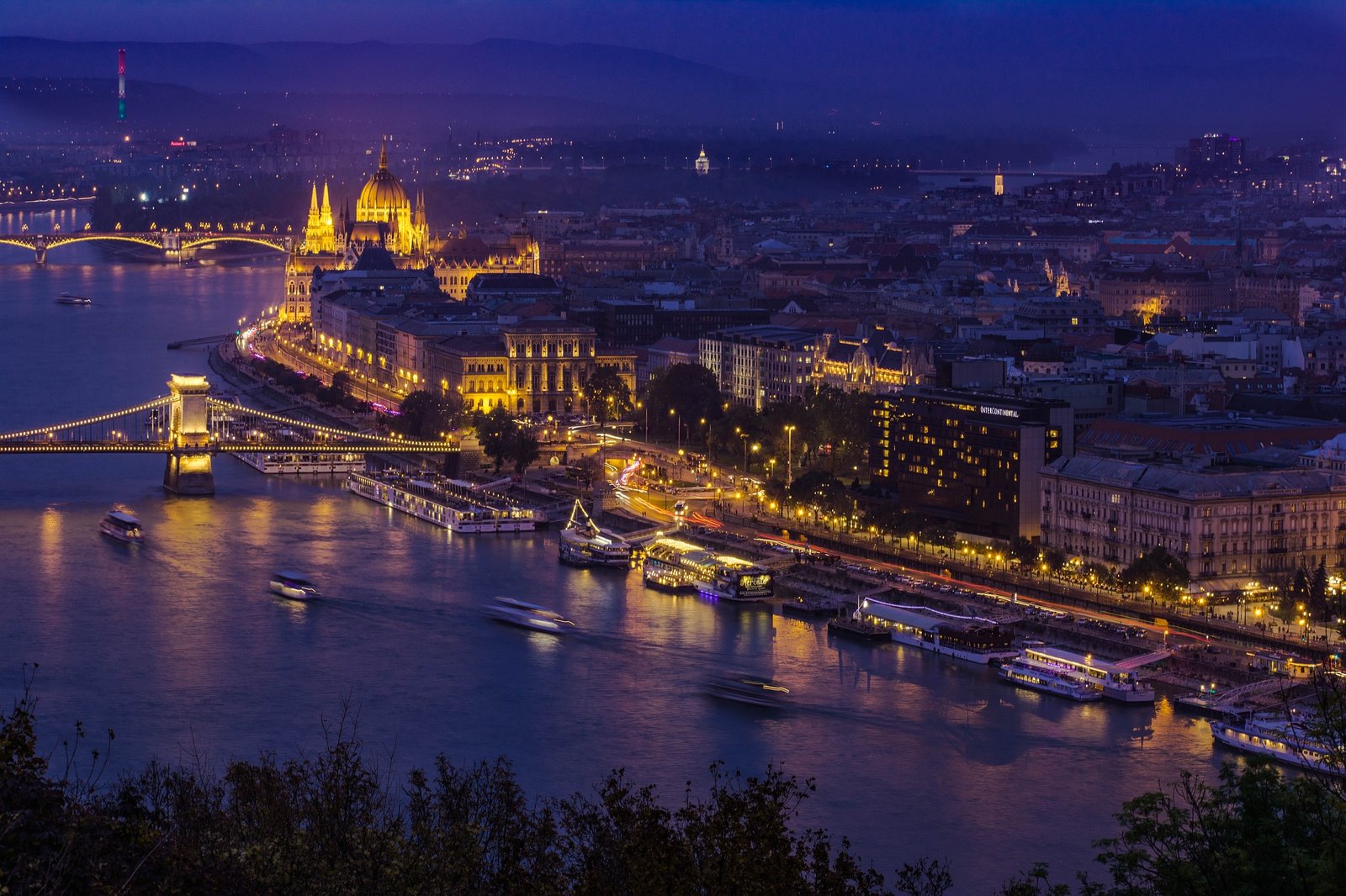 Vue aérienne de Budapest au coucher du soleil, mettant en lumière le Danube, le pont des Chaînes et le Parlement hongrois dans une ambiance dorée