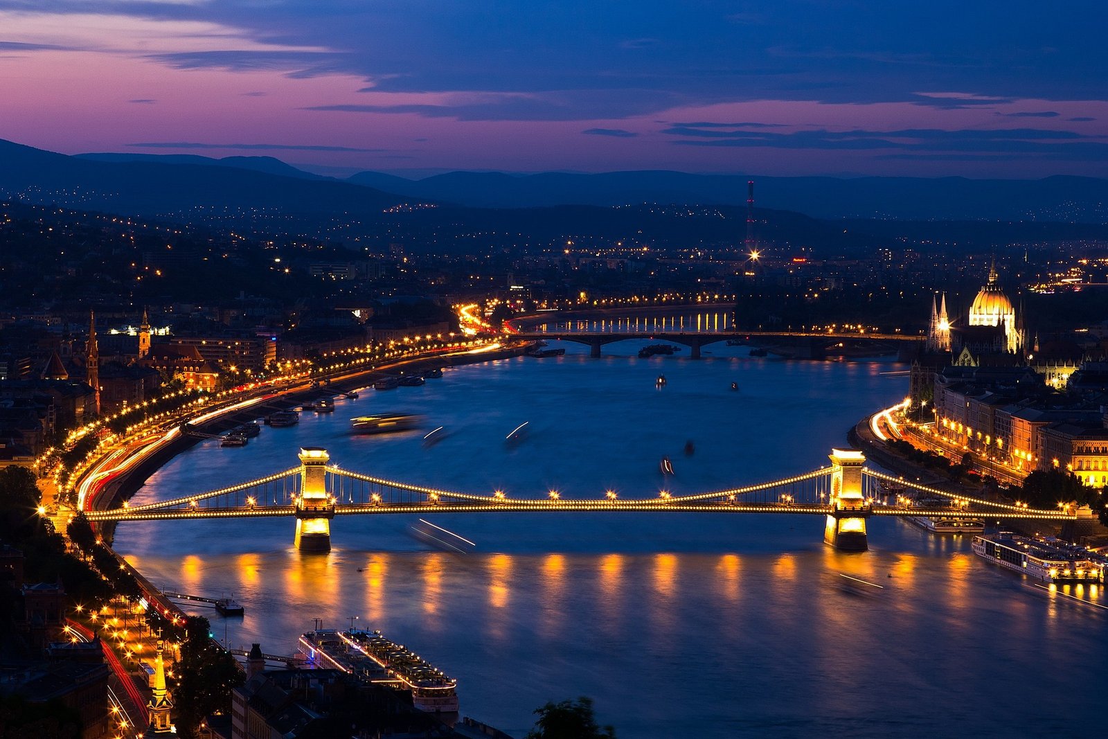 Vue aérienne de Budapest au coucher du soleil, mettant en lumière le Danube, le pont des Chaînes et le Parlement hongrois dans une ambiance dorée