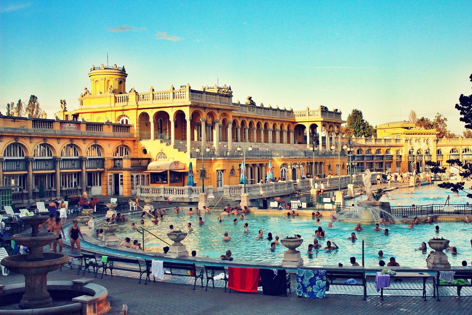 Photo des thermes de Széchenyi à Budapest en pleine journée, mettant en valeur leurs bassins d’eau chaude, leur architecture néo-baroque et l’ambiance animée du lieu