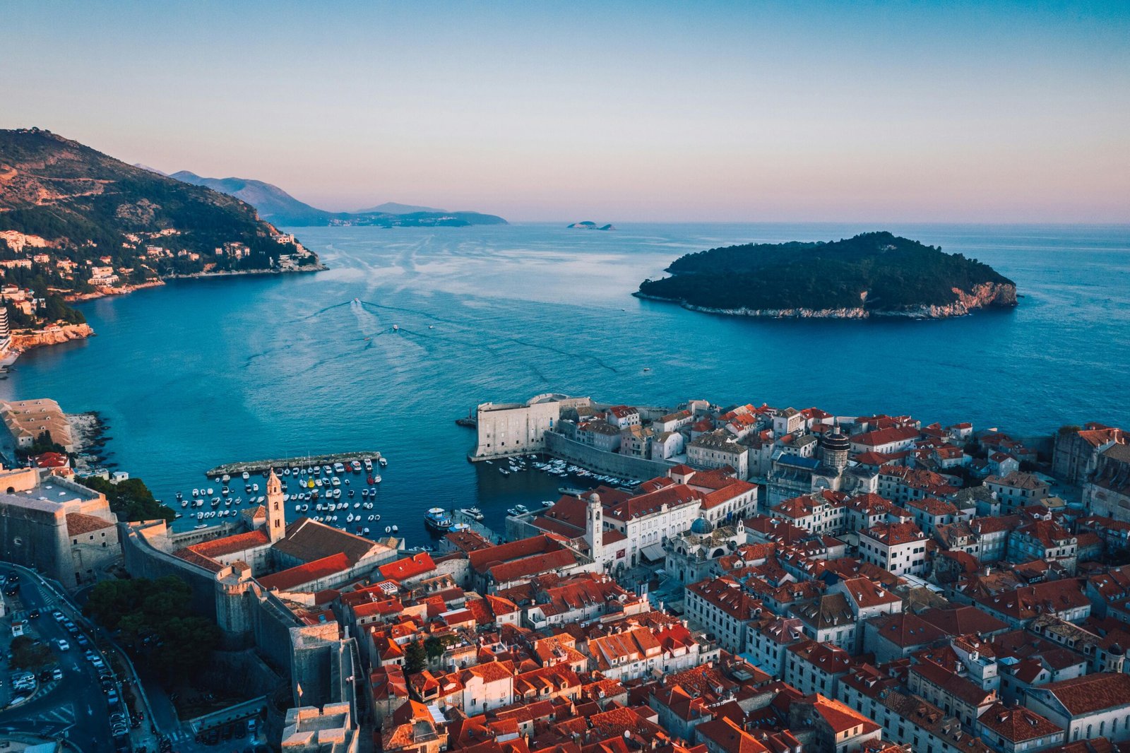 Vue aérienne sur Dubrovnik avec ses murs historiques, le port animé, et la mer Adriatique s'étendant en arrière-plan