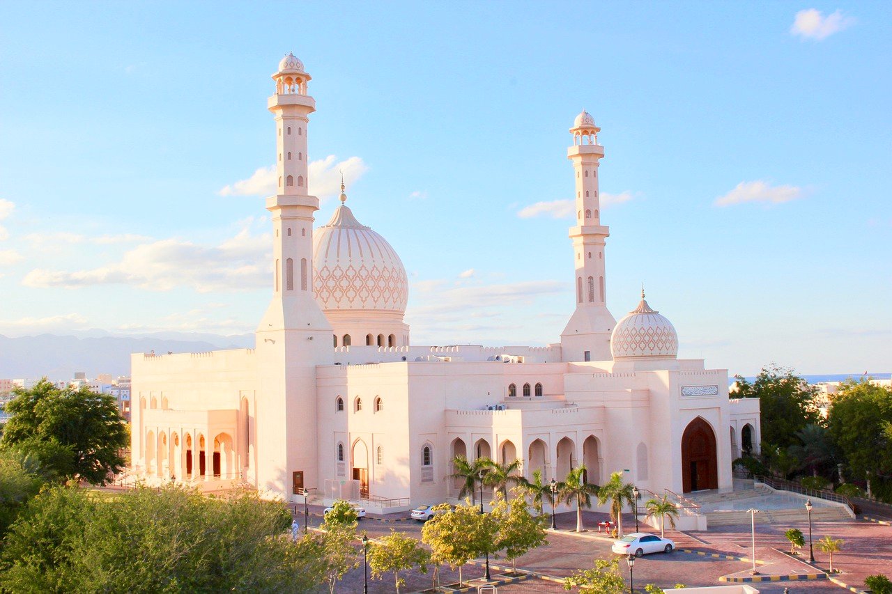 Superbe mosquée blanche à Oman, mettant en valeur son architecture élégante et ses détails raffinés sous un ciel lumineux du Moyen-Orient