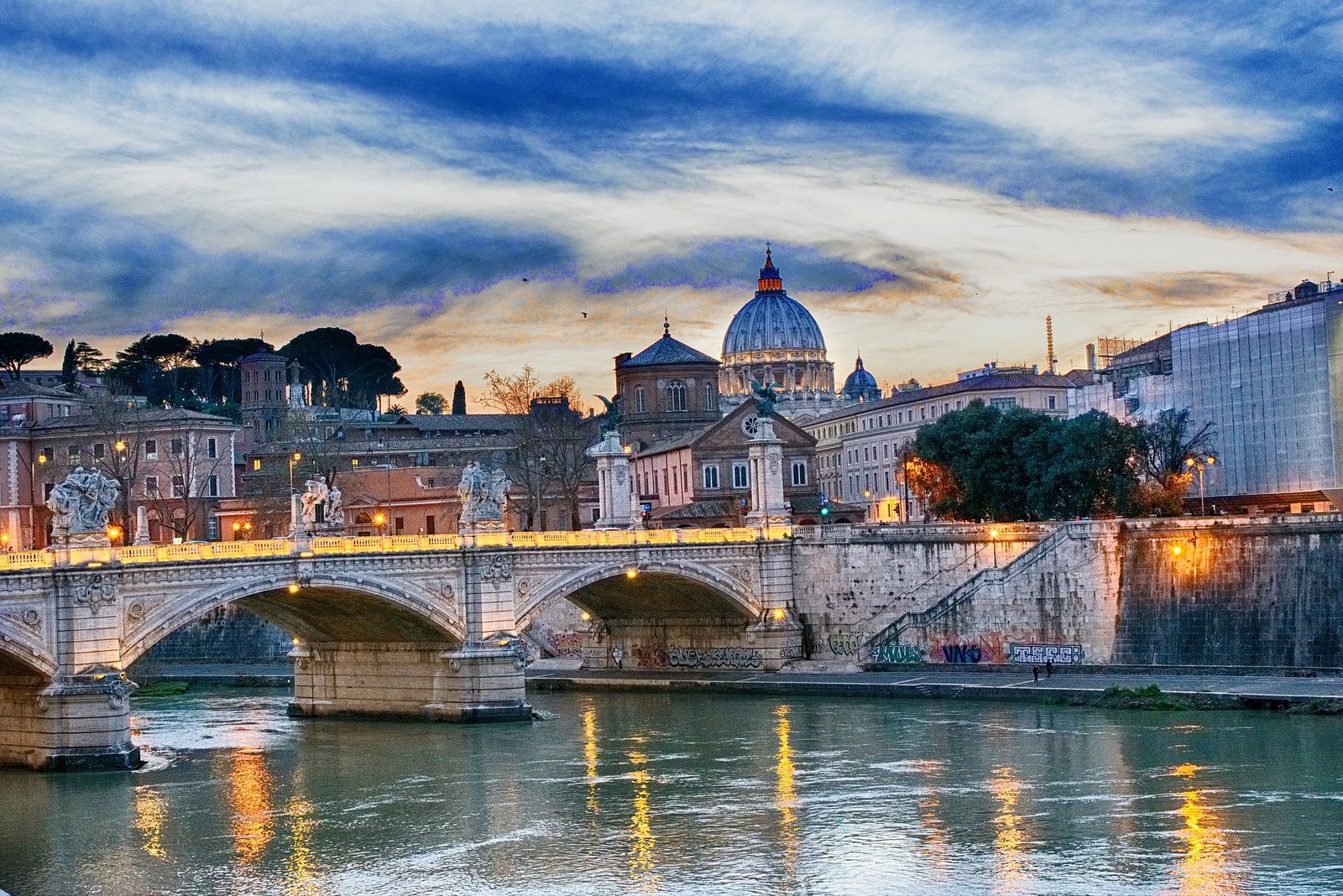 Vue sur le Pont Umberto I, élégant et majestueux, avec la Basilique Saint-Pierre en arrière-plan, se détachant à l’horizon dans une composition harmonieuse au-dessus du Tibre