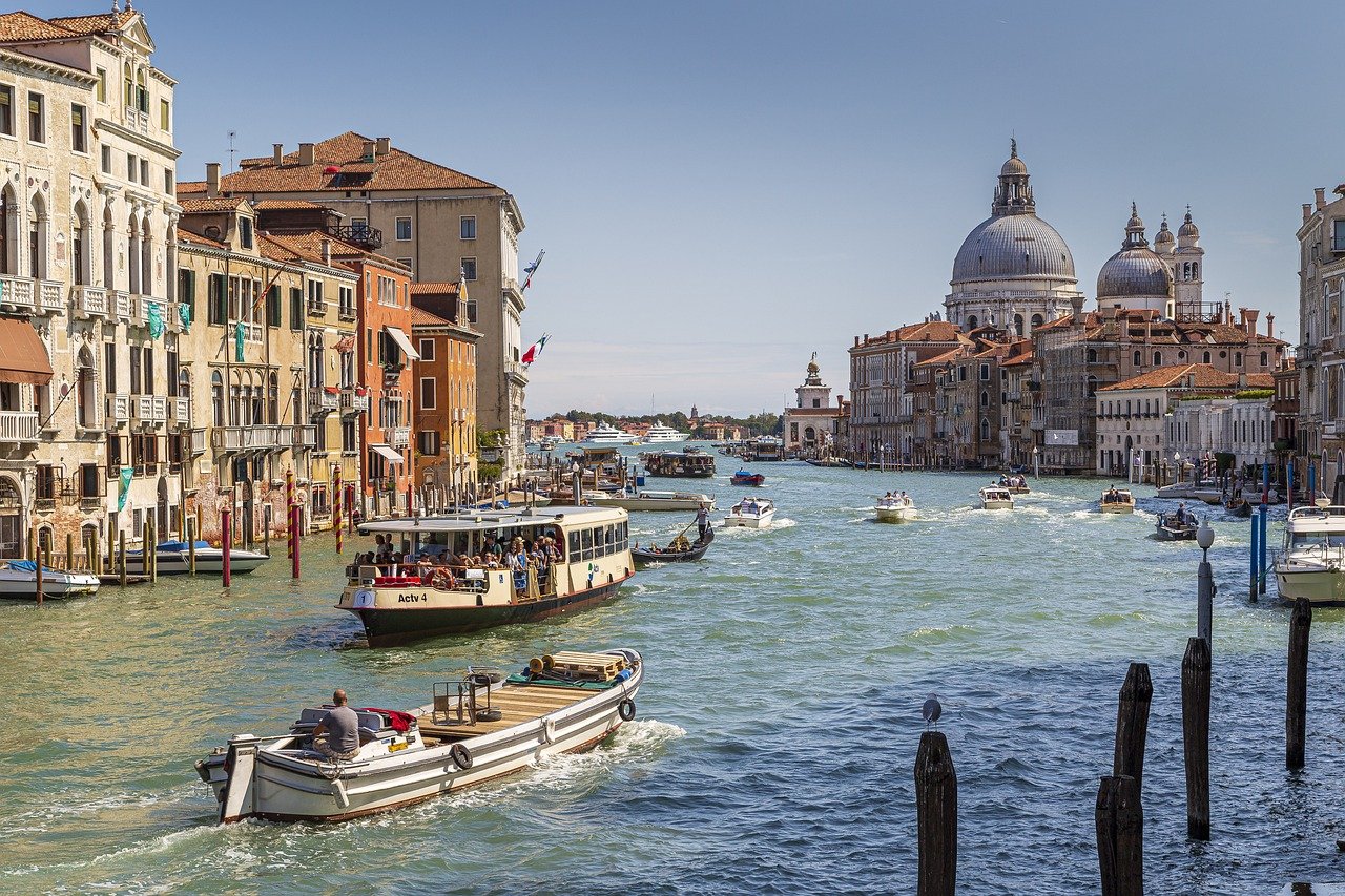 Canal pittoresque de Venise, entouré de maisons colorées, avec des gondoles et bateaux, et la Basilique Saint-Marc visible en arrière-plan