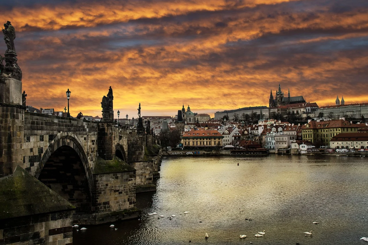 Vue panoramique sur la ville de Prague avec le pont Charles en premier plan et le château de Prague en arrière-plan, offrant un paysage emblématique de la capitale tchèque