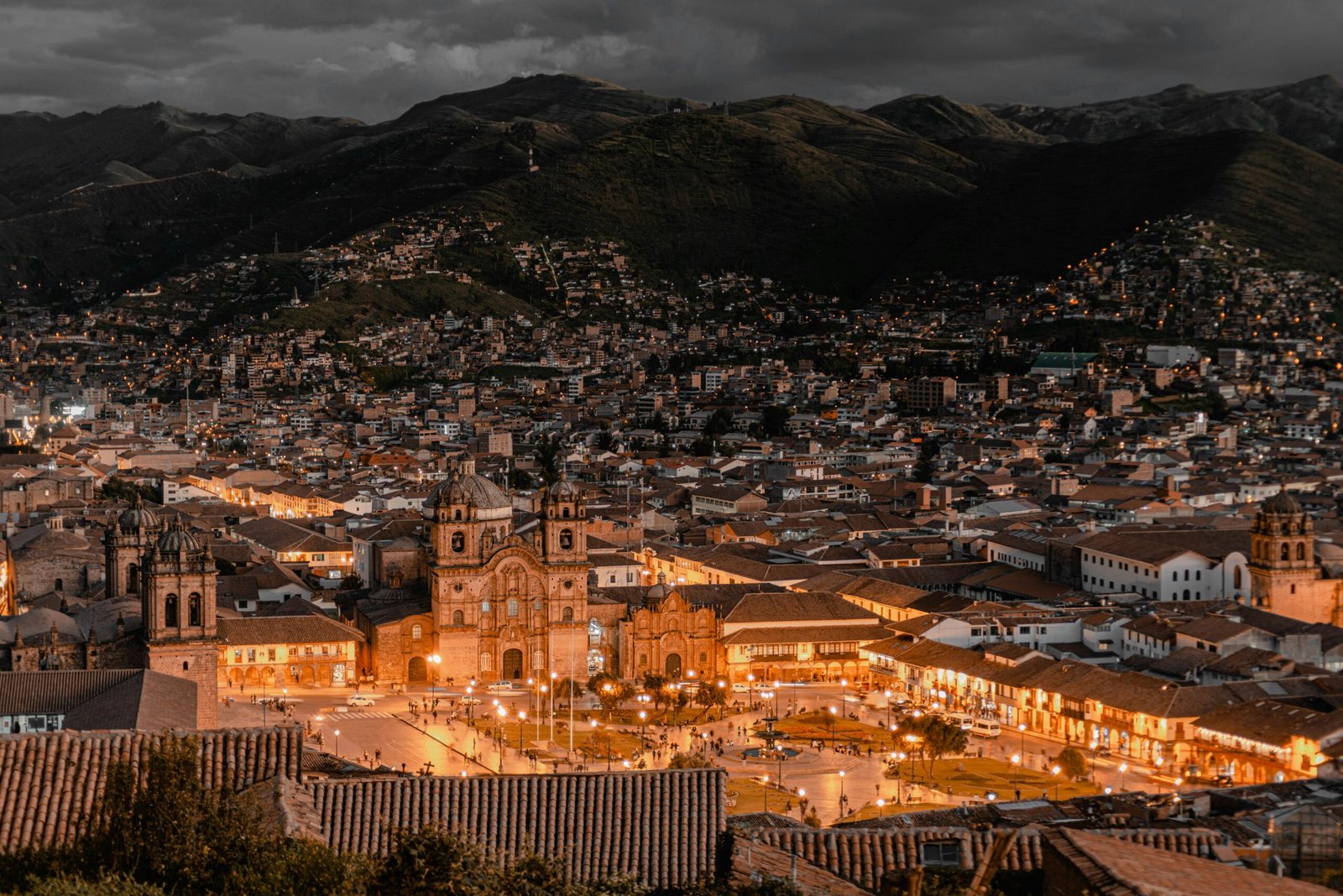 Vue panoramique de la ville de Cuzco, Pérou, illuminée à la tombée de la nuit, avec ses rues historiques et ses montagnes andines en arrière-plan