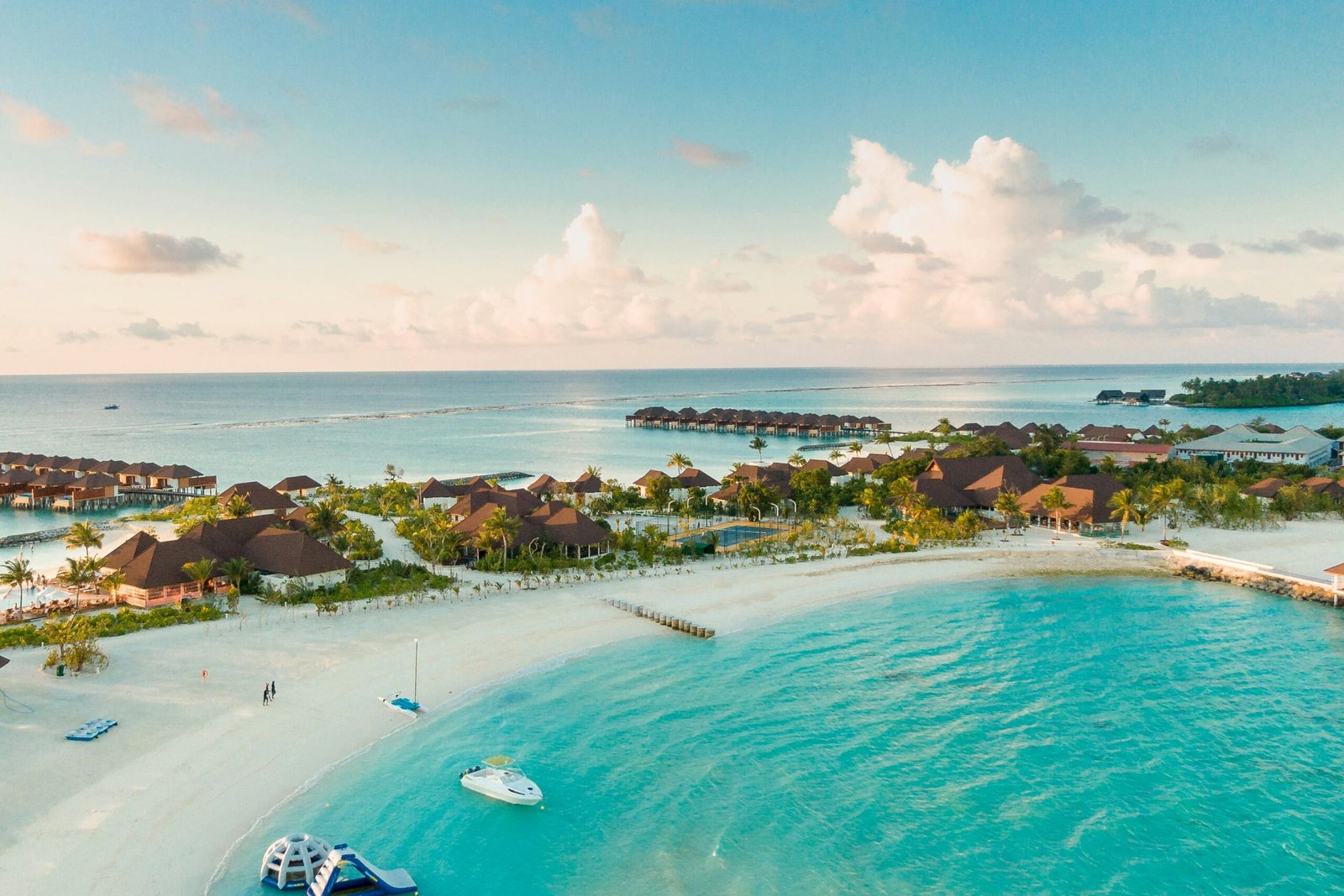 Vue aérienne d’une île paradisiaque aux Maldives, entourée d’eaux turquoise cristallines et de plages de sable blanc, offrant un décor tropical idylliques