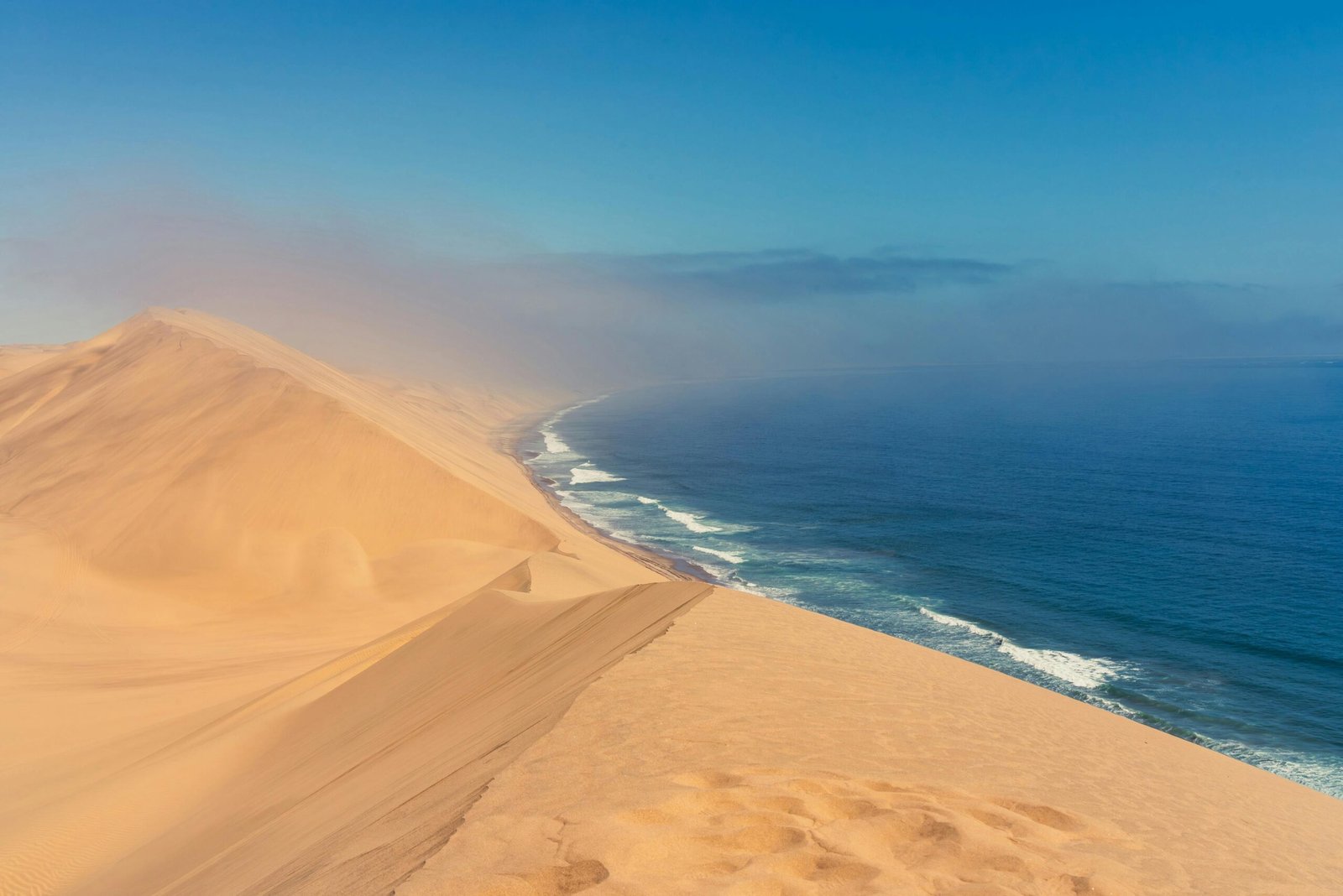Spectaculaires dunes de sable en Namibie rencontrant l’océan Atlantique, créant un contraste unique entre le désert et la mer