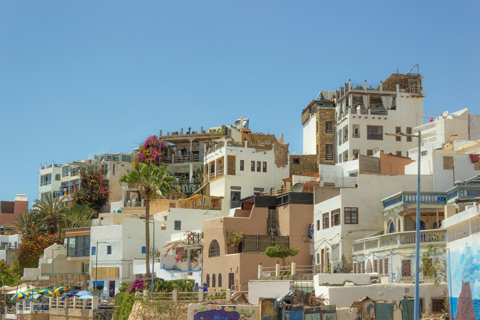 Vue sur les maisons de la ville d’Agadir, mêlant architecture moderne et traditionnelle marocaine, avec des bâtiments blancs et ocres sous un ciel clair