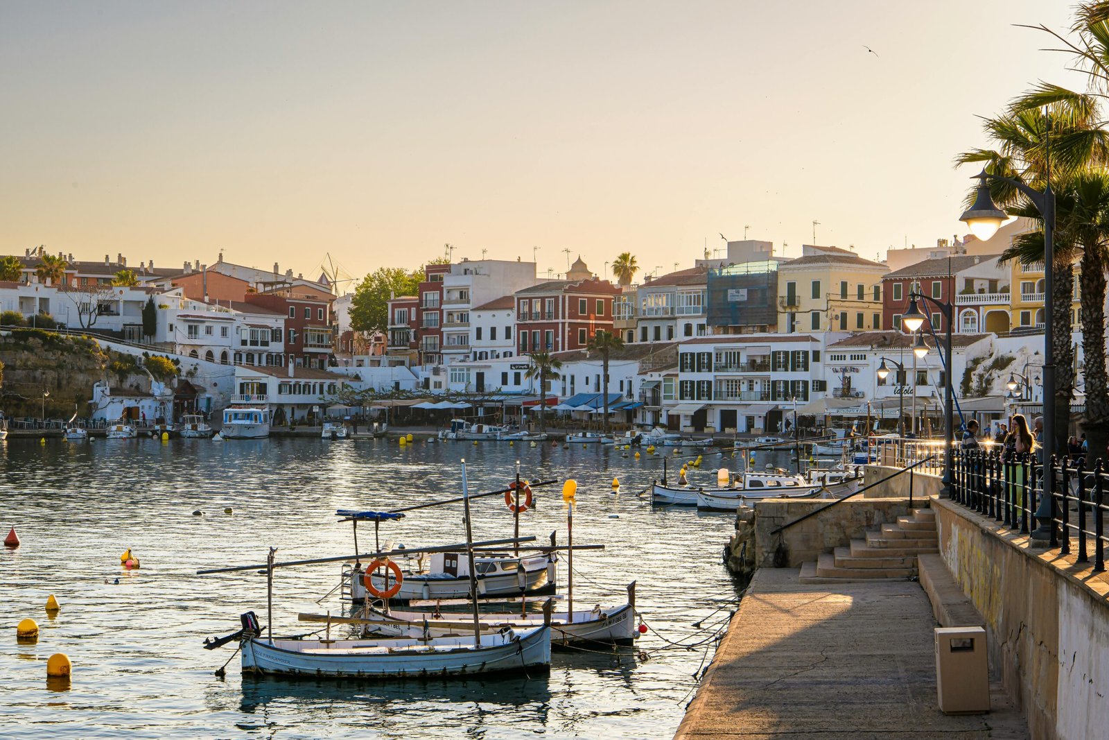 Village pittoresque à Minorque avec ses maisons blanches traditionnelles et un bateau amarré sur les eaux calmes du port