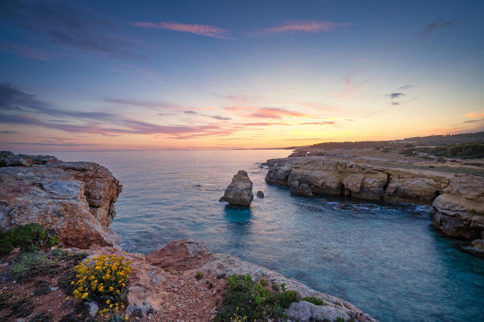 Coucher de soleil doré près de la côte de Minorque, illuminant les falaises rocheuses et la mer calme aux reflets chaleureux