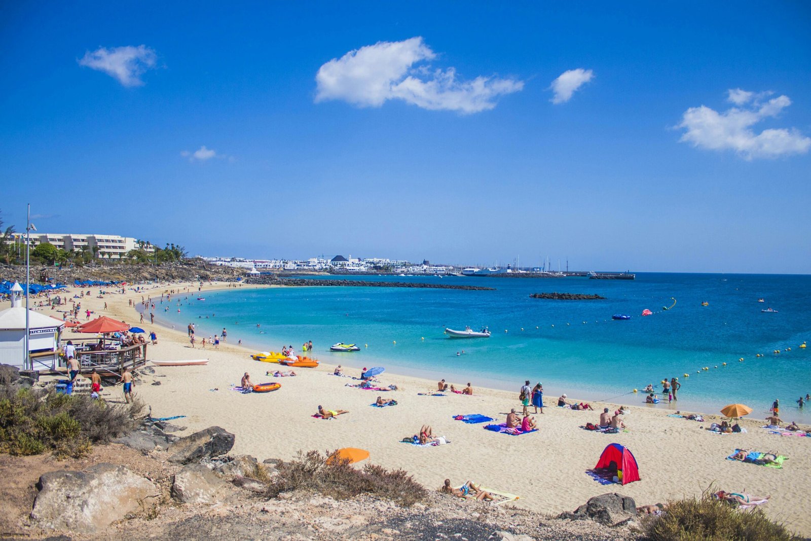 Plage de Lanzarote en pleine journée, avec du sable doré, des vagues douces et l'océan Atlantique sous un ciel ensoleillé