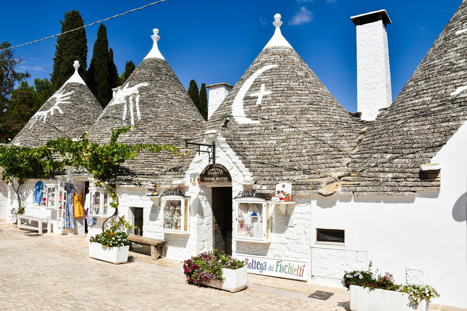 Village d’Alberobello dans les Pouilles, avec ses maisons atypiques en pierre appelées trulli, aux toits coniques caractéristiques, sous un ciel bleu éclatant