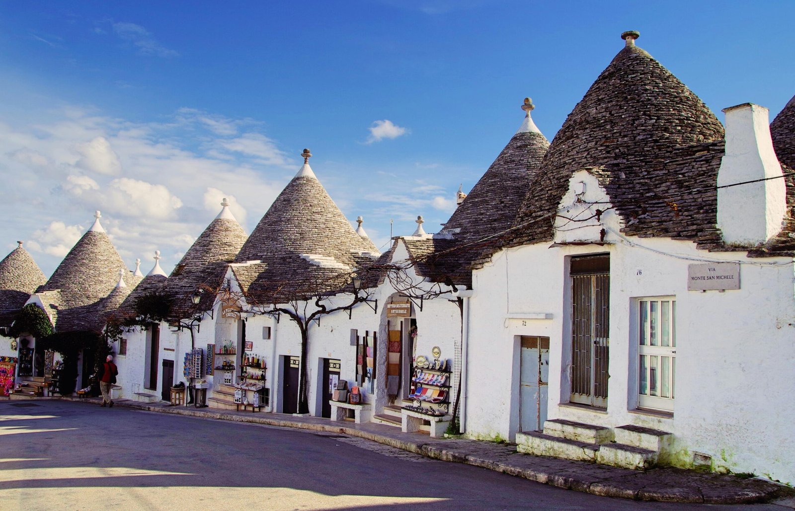 Village d’Alberobello dans les Pouilles, avec ses maisons atypiques en pierre appelées trulli, aux toits coniques caractéristiques, sous un ciel bleu éclatant