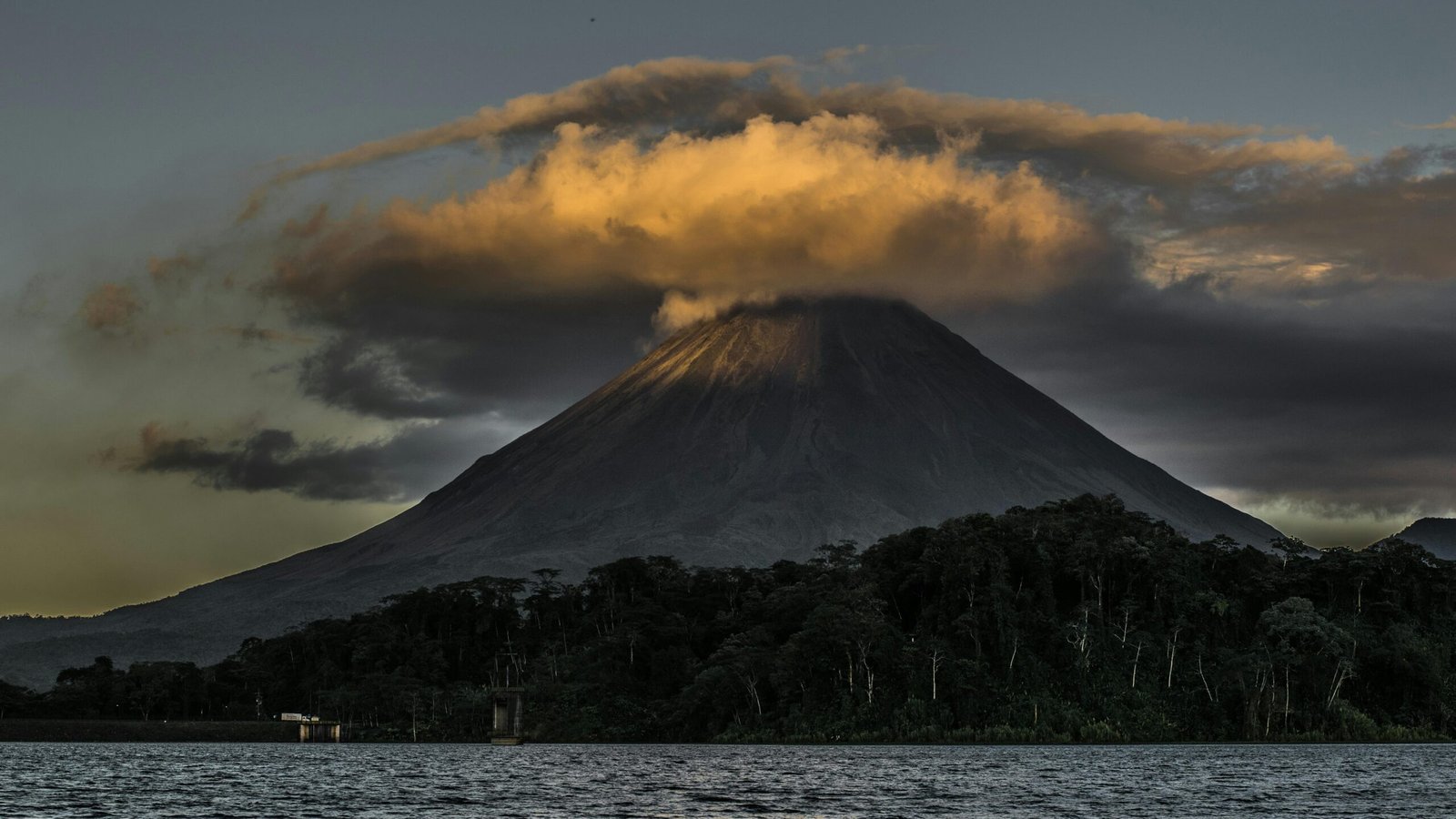 Vue panoramique sur un volcan majestueux du Costa Rica en arrière-plan, avec une plage tropicale bordée de palmiers au premier plan