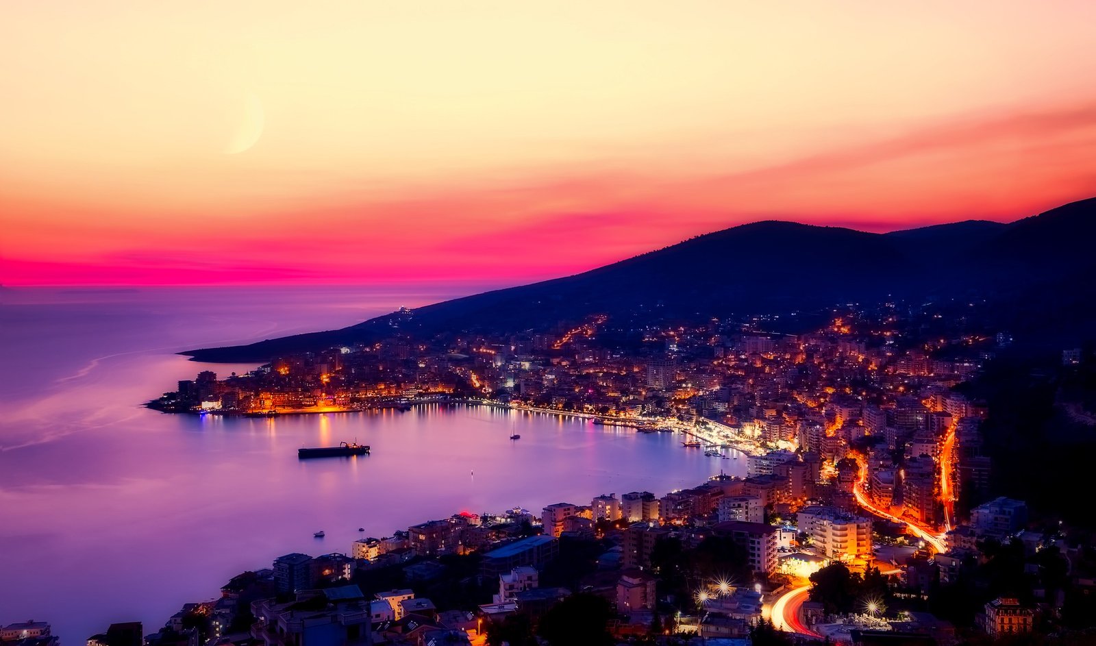 Vue panoramique sur la ville côtière de Saranda, en Albanie illuminée par les teintes chaudes du coucher de soleil, avec la mer Ionienne scintillante à l'horizon
