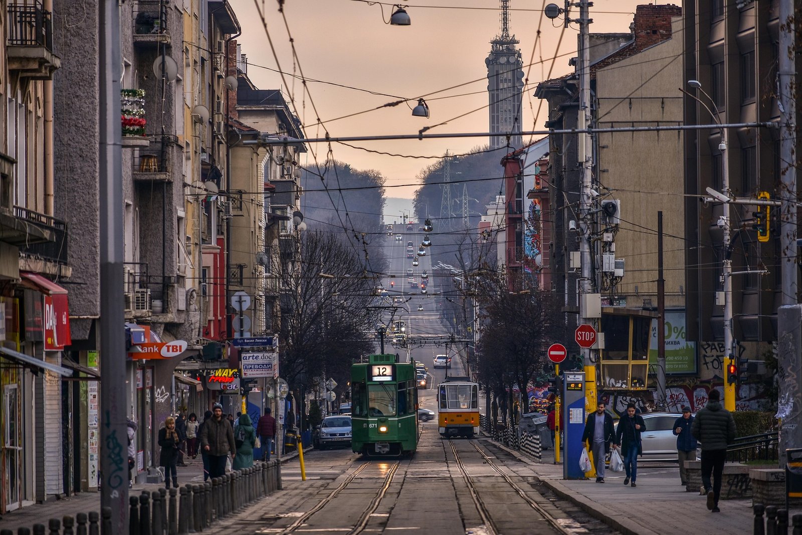 Rue animée de Sofia au coucher du soleil, avec lignes de tramway, circulation et architecture urbaine