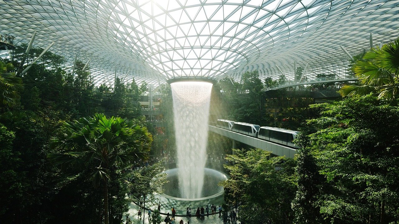 Vue sur la célèbre cascade intérieure de l'aéroport Jewel Changi à Singapour, entourée de végétation luxuriante sous une verrière spectaculaire