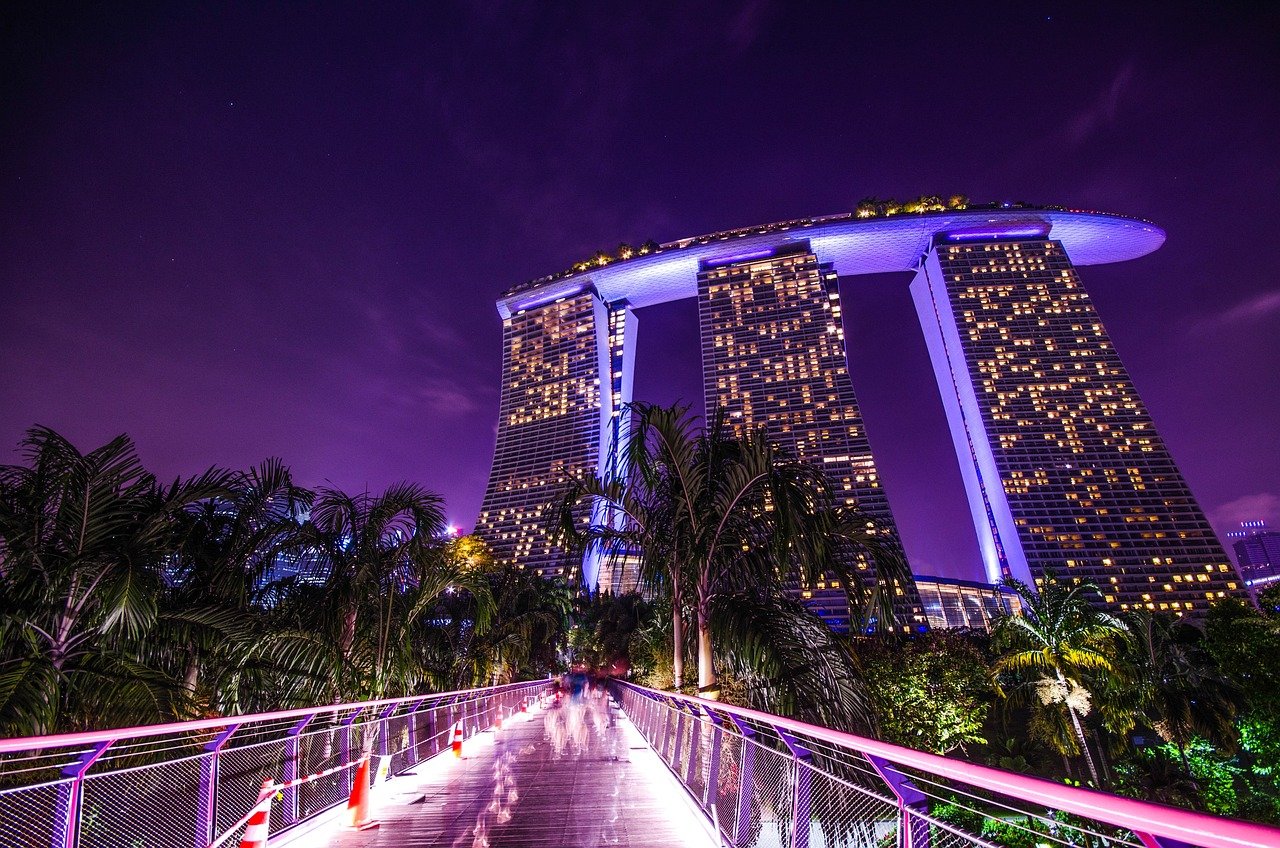 Vue emblématique sur le Marina Bay Sands à Singapour, avec ses trois tours surmontées de la SkyPark, éclairées la nuit en bord de baie